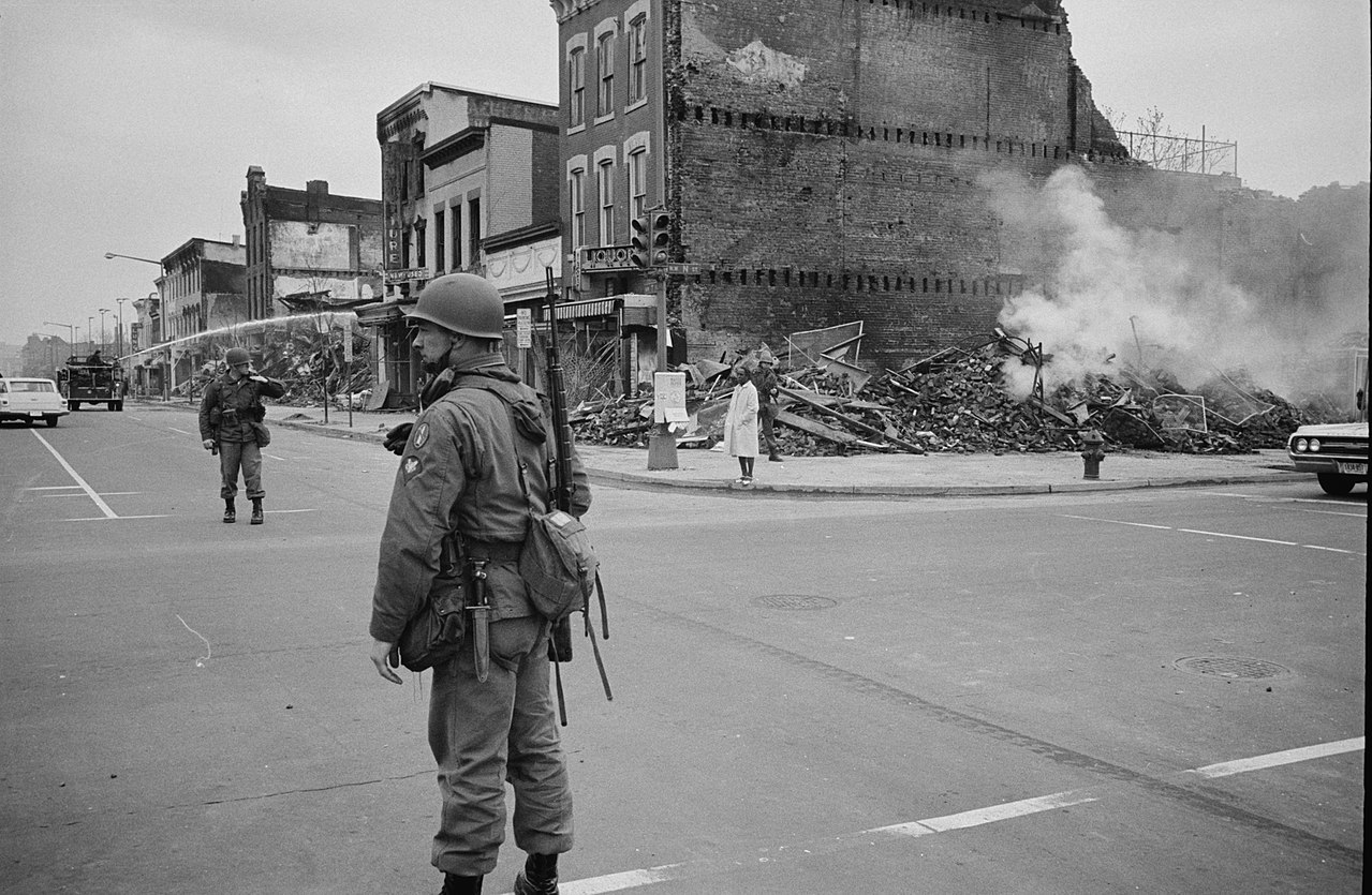 Soldier standing guard on the corner of 7th & N Street NW in Washington D.C. with the ruins of buildings that were destroyed during the uprisings that followed the assassination of Martin Luther King, Jr. Date: 8 April 1968 Credit: Warren K. Leffler/Library of Congress.