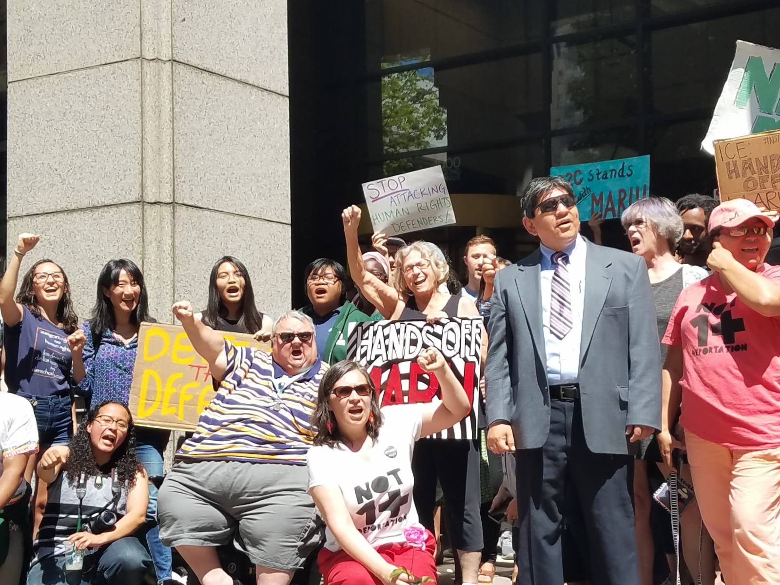 Maru Mora-Villalpando, center, kneeling, with supporters in front of immigration court building. Liberation photo.