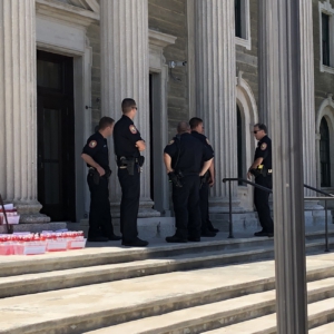 Police on County Building steps with water bottles containing red dye that were used by activists as a theater prop. Photo: PANIC.
