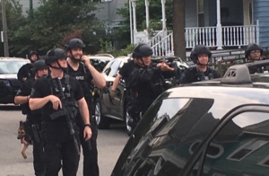 heavily armed Boston Police officers smile as they walk through Dorchester