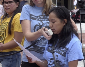 An anti-ICE activist reads from a paper into a megaphone held by another activist.