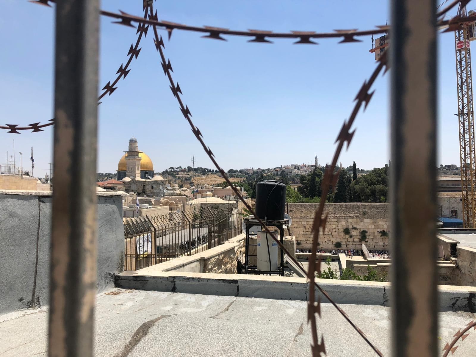 A view from a window with wire across it of Occupied East Jerusalem, overlooking the Dome of the Rock in Al-Aqsa.