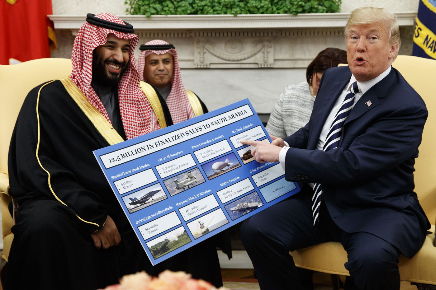 Donald Trump and Mohammed bin Salman sit on a couch together, looking at a large board with information on it.