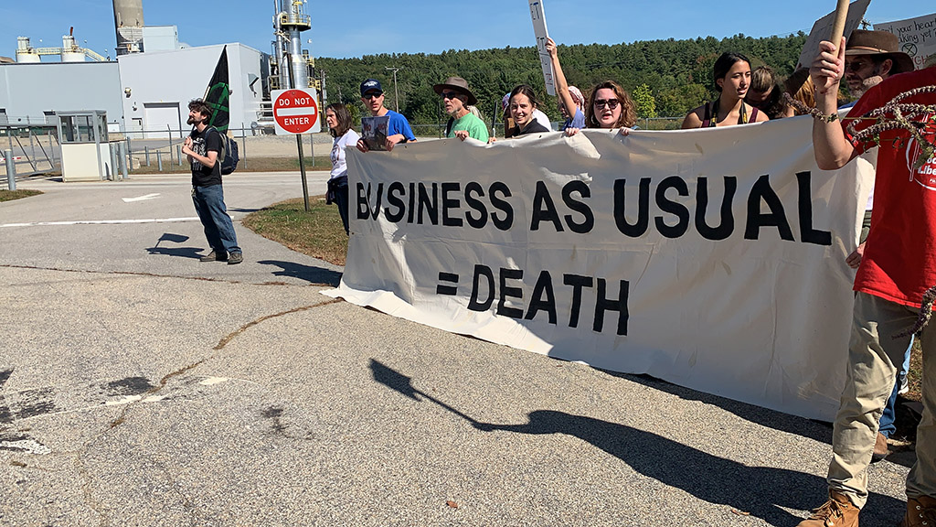 Activists hold banner that reads "Business as usual = death" in New Hampshire.