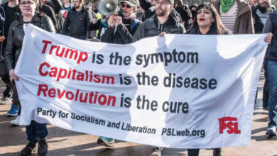 A group of people hold a banner that reads, "Trump is the symptom, Capitalism is the disease, Revolution is the cure". The banner reads "Party for Socialism and Liberation, pslweb.org"
