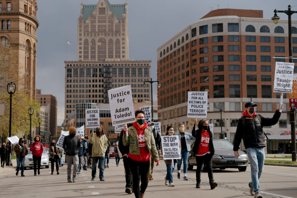 Marchers and car caravan passing Milwaukee City Hall. Liberation photo Nathan Schmidt