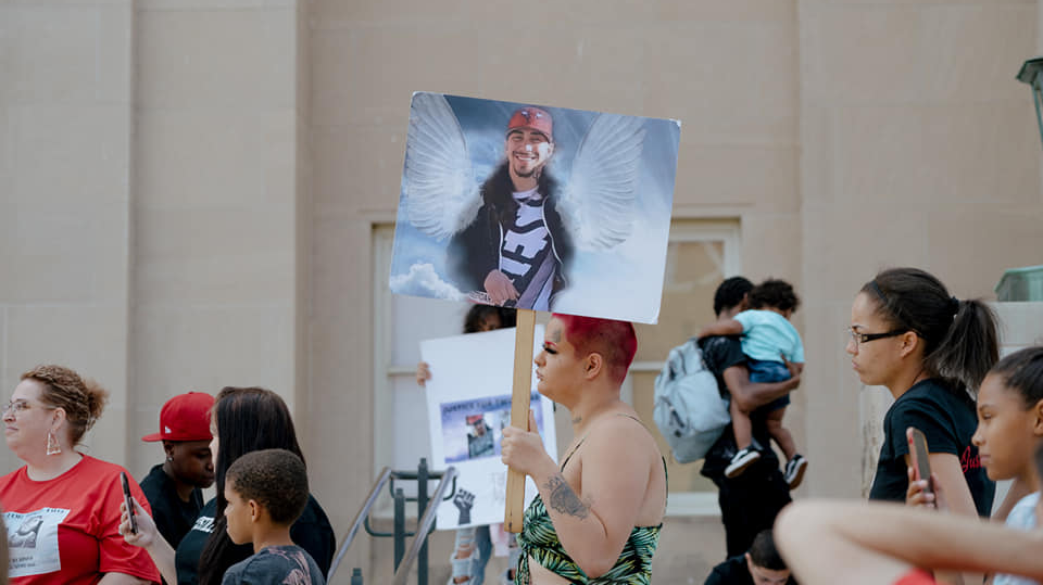 A protester holds a sign memorializing Ronquale Ditello-Scott. Liberation photo