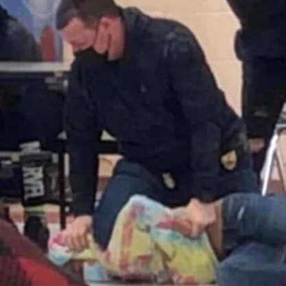 Off-duty police officer Shawn Guetschow kneeling on a 12-year-old girl's neck. From surveillance video released by Kenosha Unified School District.